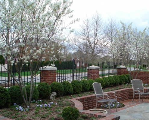 A metal fence with brick pillars surrounding a finished landscape