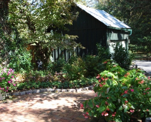 A thriving garden next to a brick walkway with a flower pot accent
